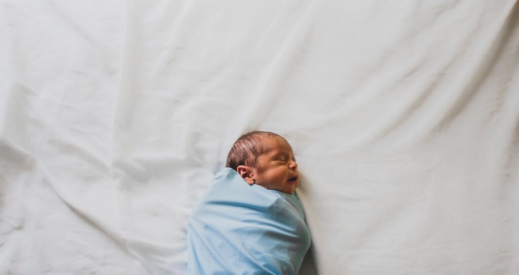 Baby boy in blue swaddling | 5 Essentials Newborn Baby Products You Need As A First Time Mom | Baby Tips | Elle Blonde Luxury Lifestyle Destination Blog | Paternity Test