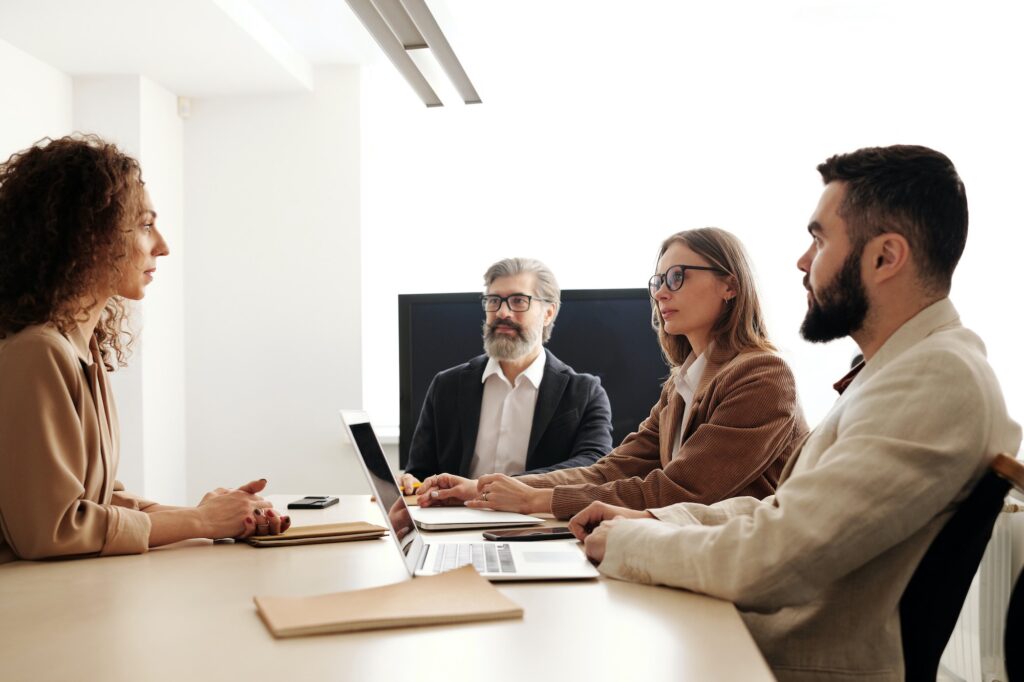 Two men and two women sitting at a table | What Do You Need To Be An HR Consultant? | Business & Education | Elle Blonde Luxury Lifestyle Destination Blog | Workplace Anxiety