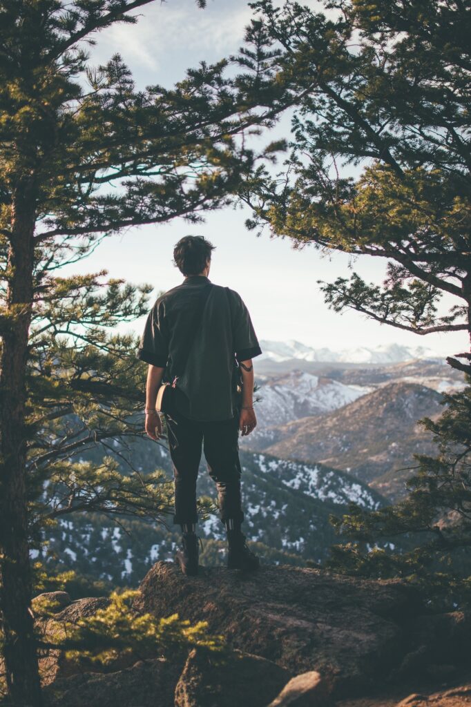 Man looking through trees at mountain |  Where to find mountain land for sale | Home Interiors | Elle Blonde Luxury Lifestyle Destination Blog