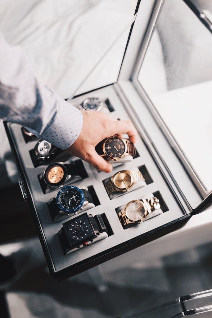 The Art of Intentional Elegance: Curating the Perfect Timepiece 3 Timepiece - A sophisticated display of luxury watches in an elegant case with a hand selecting one.