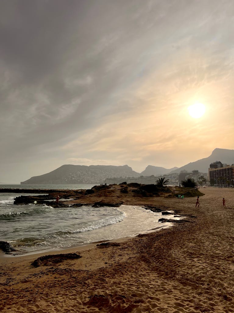 Calpe, Alicante: A Slow Living Guide to the Peñón de Ifach & Costa Blanca’s Most Iconic Coastal Landscape 3 A tranquil view of Calpe beach during sunset, showcasing the Mediterranean coast of Spain.