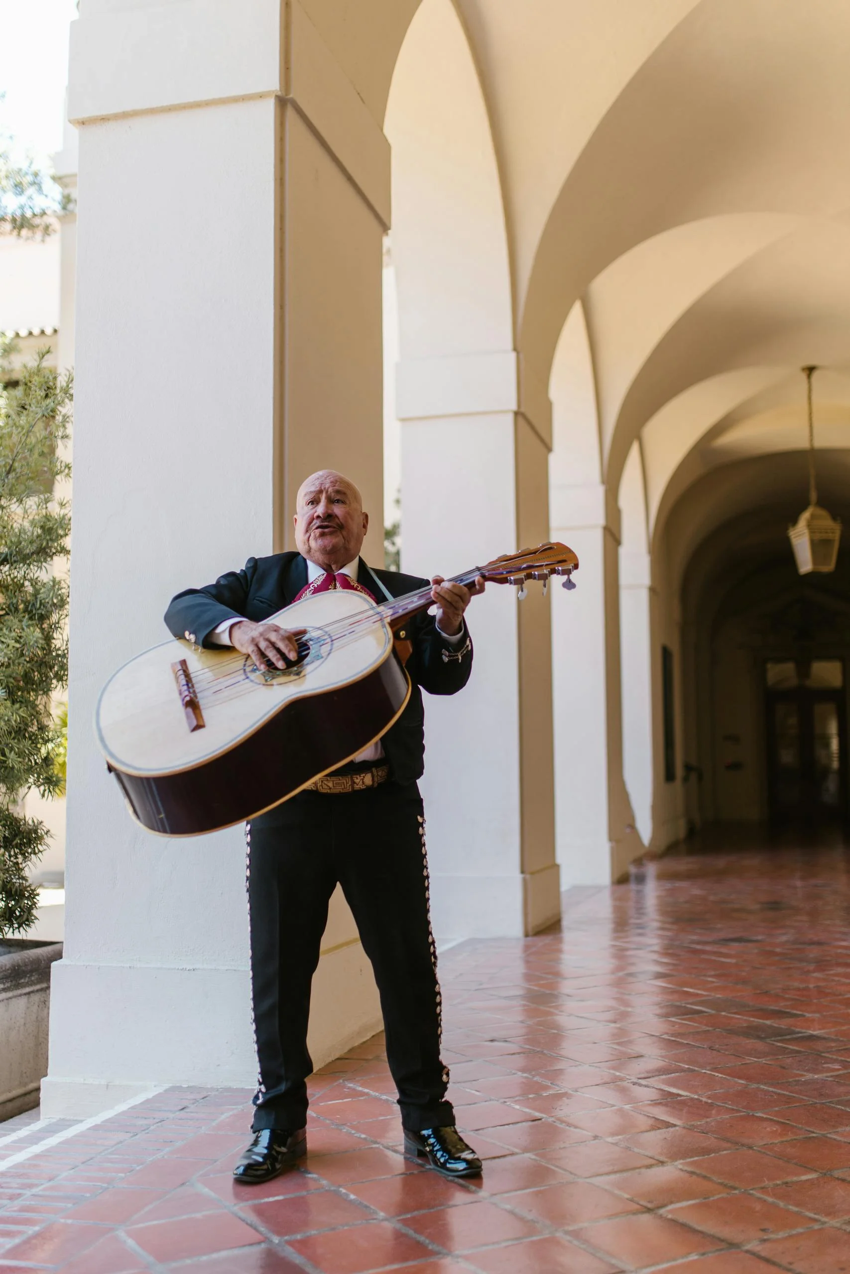 A mariachi musician performs passionately in traditional attire, playing a Mexican guitarron.