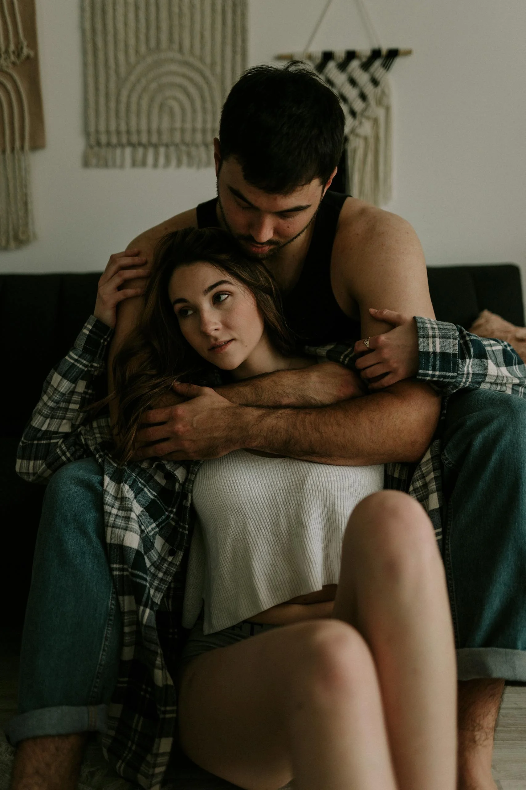 A young couple shares an intimate embrace on a sofa in a modern living room.