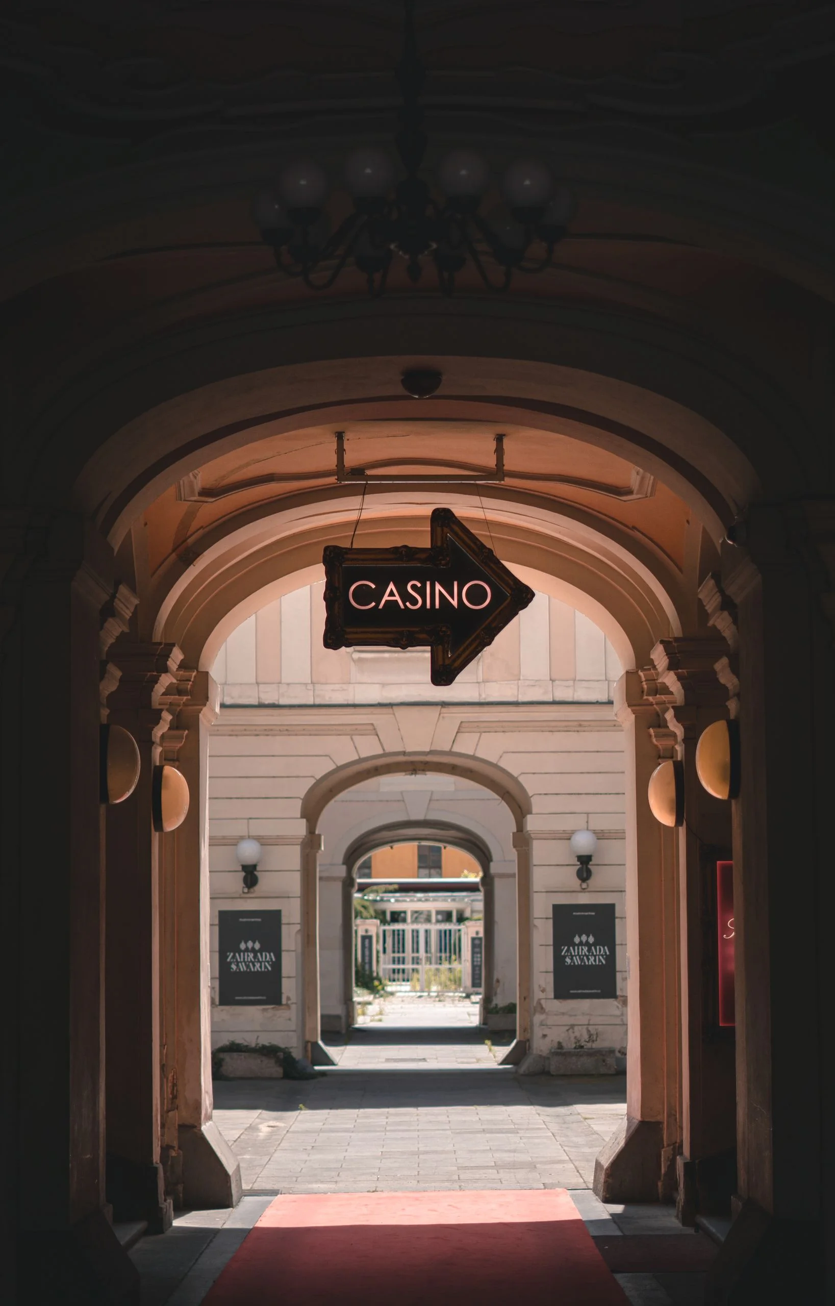 View through arched passage leading to casino, marked by a glowing arrow sign.