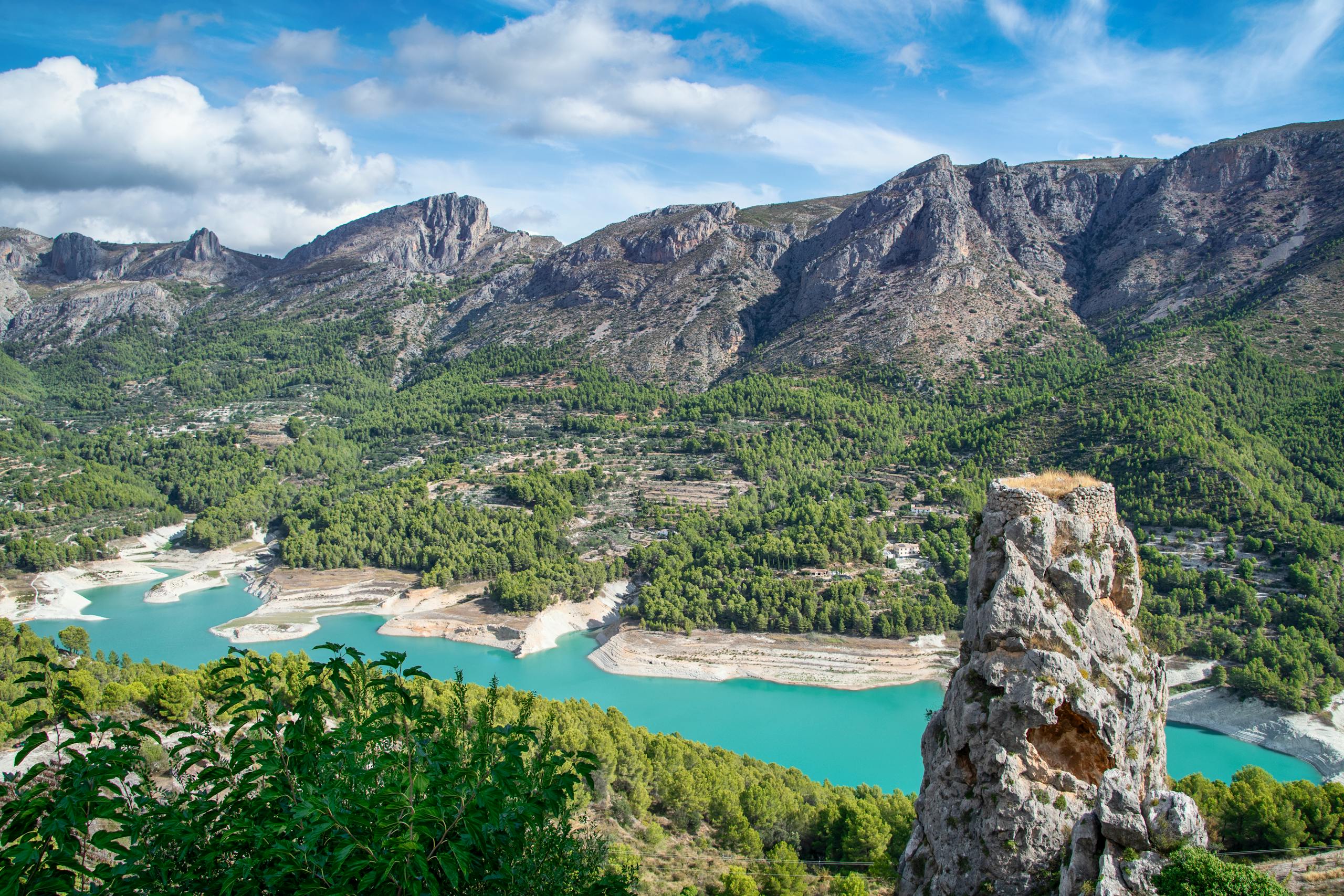Breathtaking view of Guadalest Valley with turquoise reservoir and rugged mountains.