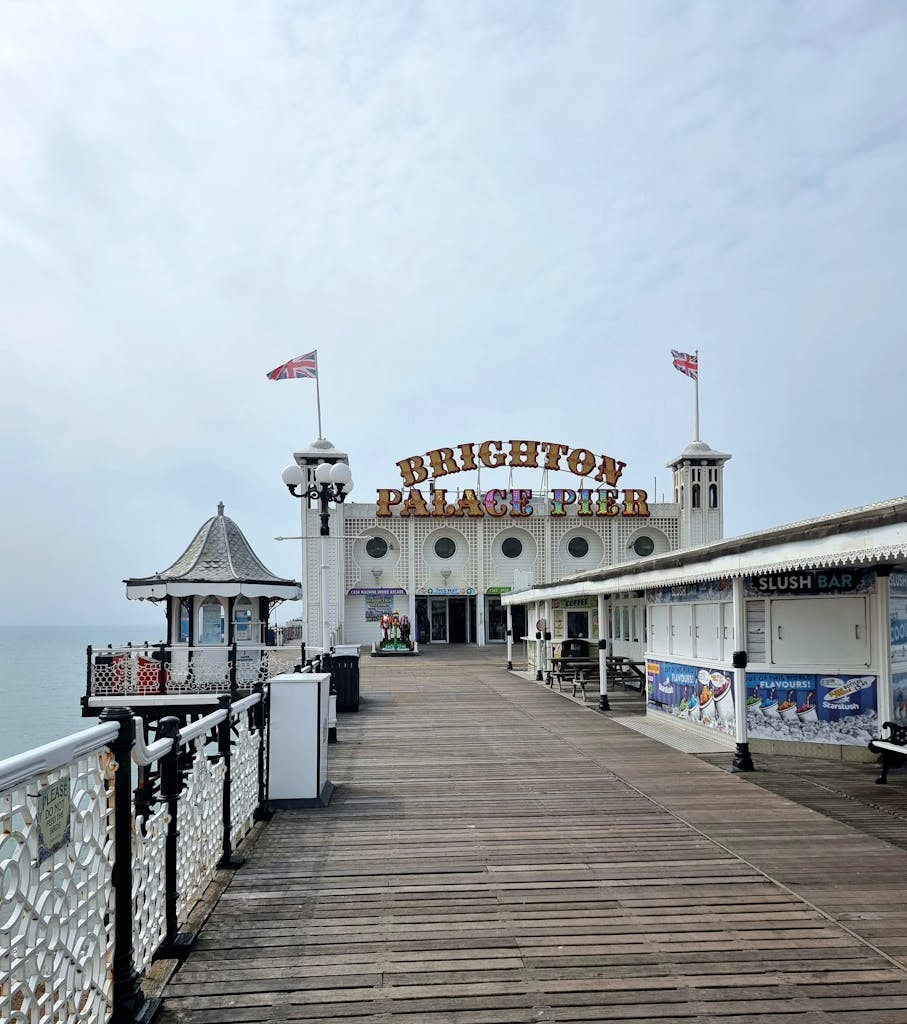 Brighton Palace Pier in England with Union Jack flags on a cloudy day.