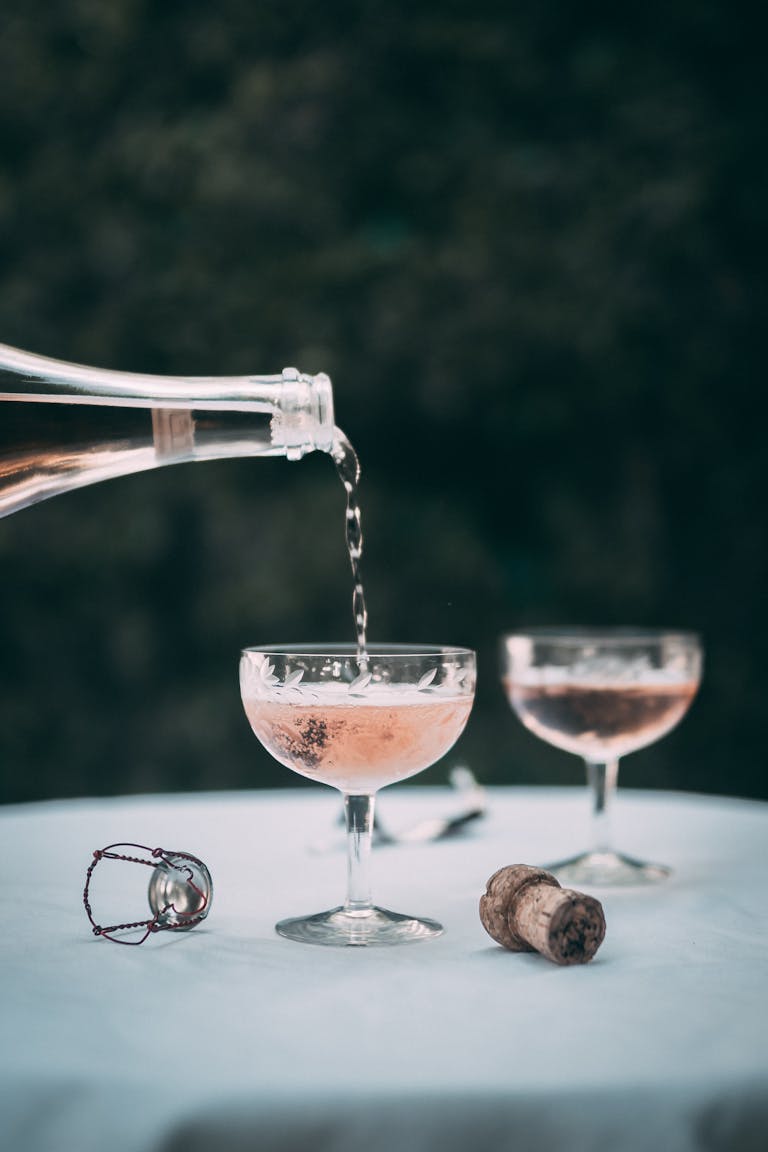 Champagne being poured into glasses on a table with cork and wire, creating an elegant setting.