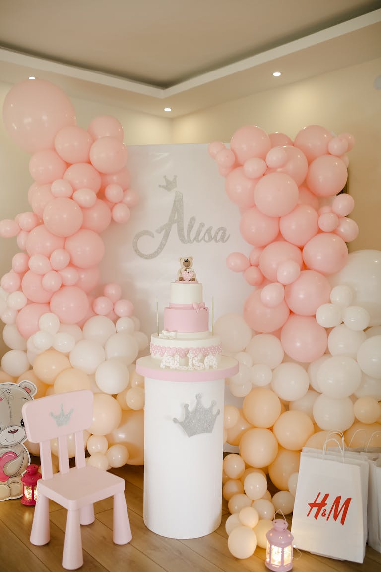 Charming birthday setup with pink balloons, cake, and decorations in an indoor setting.