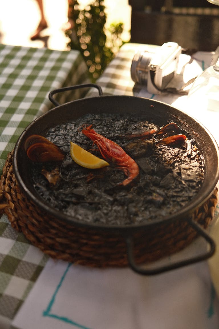 Close-up of a delicious seafood paella with shrimp and lemon on a wicker mat. Perfect for culinary themes. Fine dining in ibiza