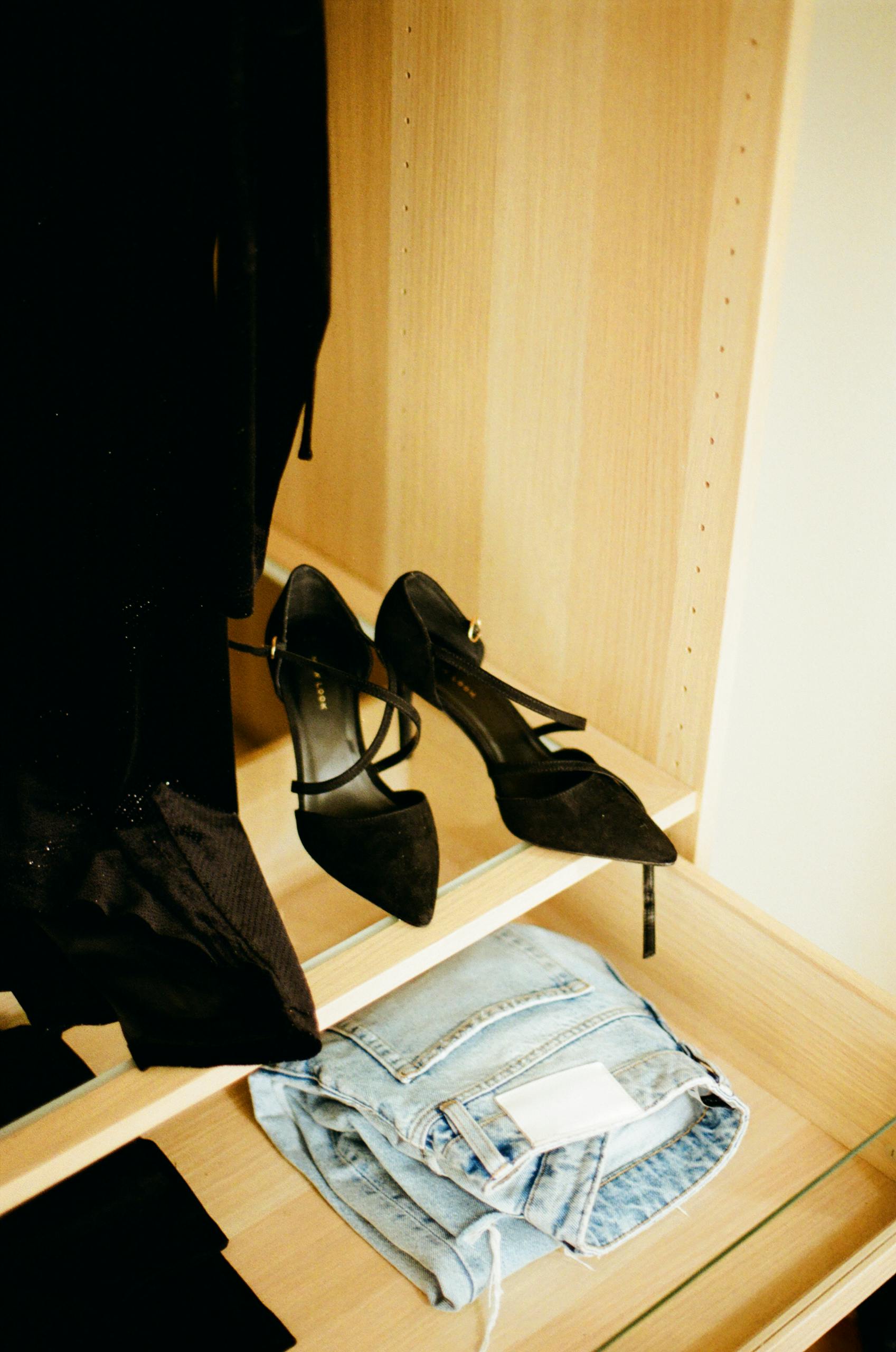 Elegant black high heels and denim jeans in a stylish wardrobe setting in Nice, France.