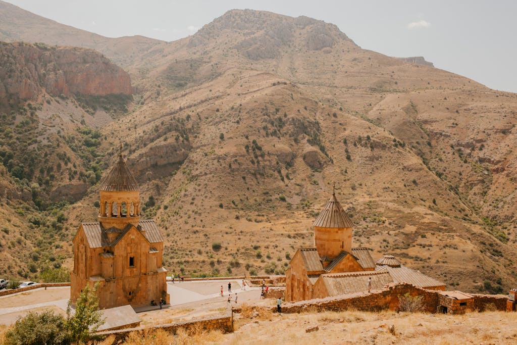 From above of travelers walking near old cathedrals located in mountainous area in sunny day