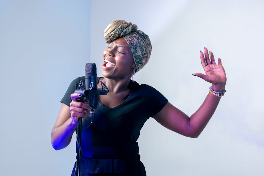 Why You Should Consider Hiring a Live Band for Your Corporate Event 3 Passionate African woman singing in a music studio with a microphone and headscarf.