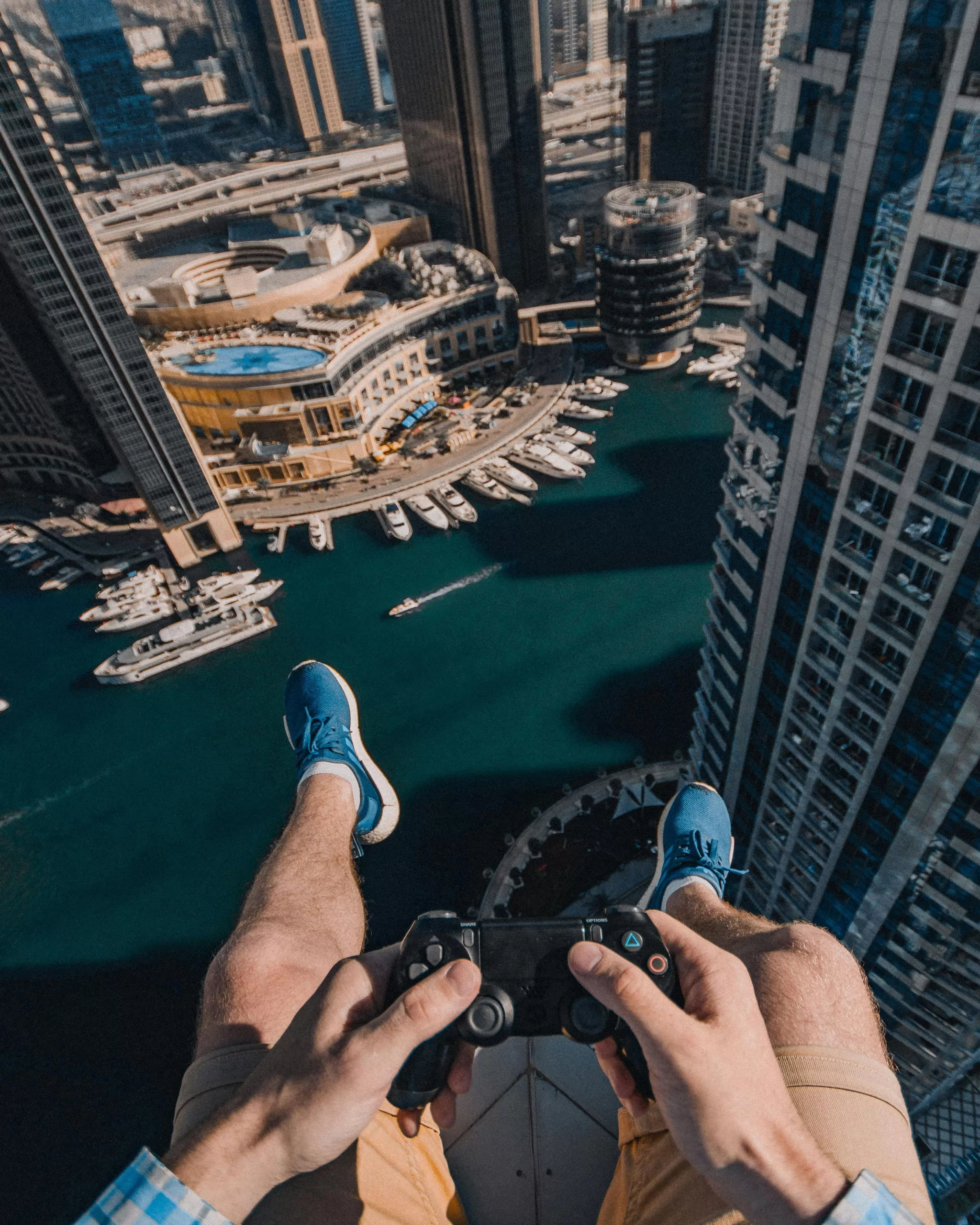 A daring rooftop view of a man holding a PlayStation controller above Dubai Marina, blending gaming with high-rise luxury and adrenaline. | Travel Tips | Elle Blonde Luxury Lifestyle Destination Blog Skill Based Gaming: A Career of the Future?