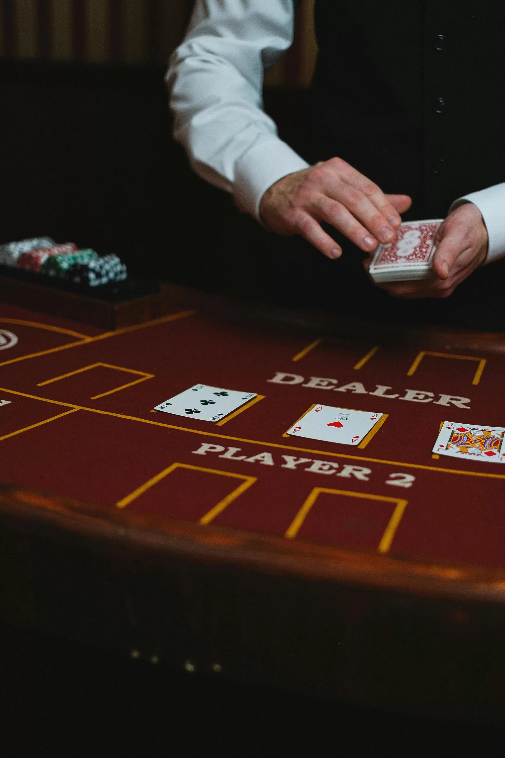 A close-up of a man’s hand elegantly holding poker chips beside a crystal glass of whisky and cigar, adorned with a sparkling diamond ring. | How to Gamble Smart and Stylishly | Elle Blonde Luxury Lifestyle Destination Blog