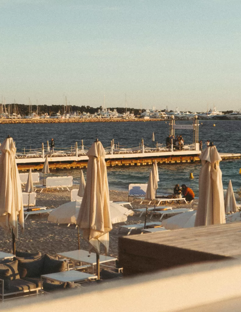 How to Make Pinterest Work Without Posting Every Day 2 Golden hour at a private beach club in Cannes, lined with white loungers and umbrellas — the epitome of Riviera glamour and laid-back indulgence | Travel Tips | Elle Blonde Luxury Lifestyle Destination Blog | Pinterest Work