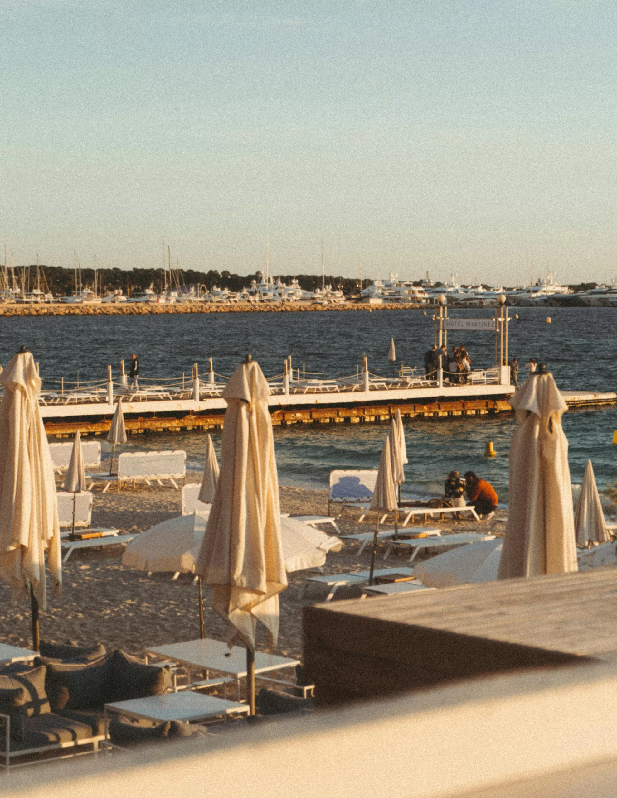 Golden hour at a private beach club in Cannes, lined with white loungers and umbrellas — the epitome of Riviera glamour and laid-back indulgence | Travel Tips | Elle Blonde Luxury Lifestyle Destination Blog | Pinterest Work