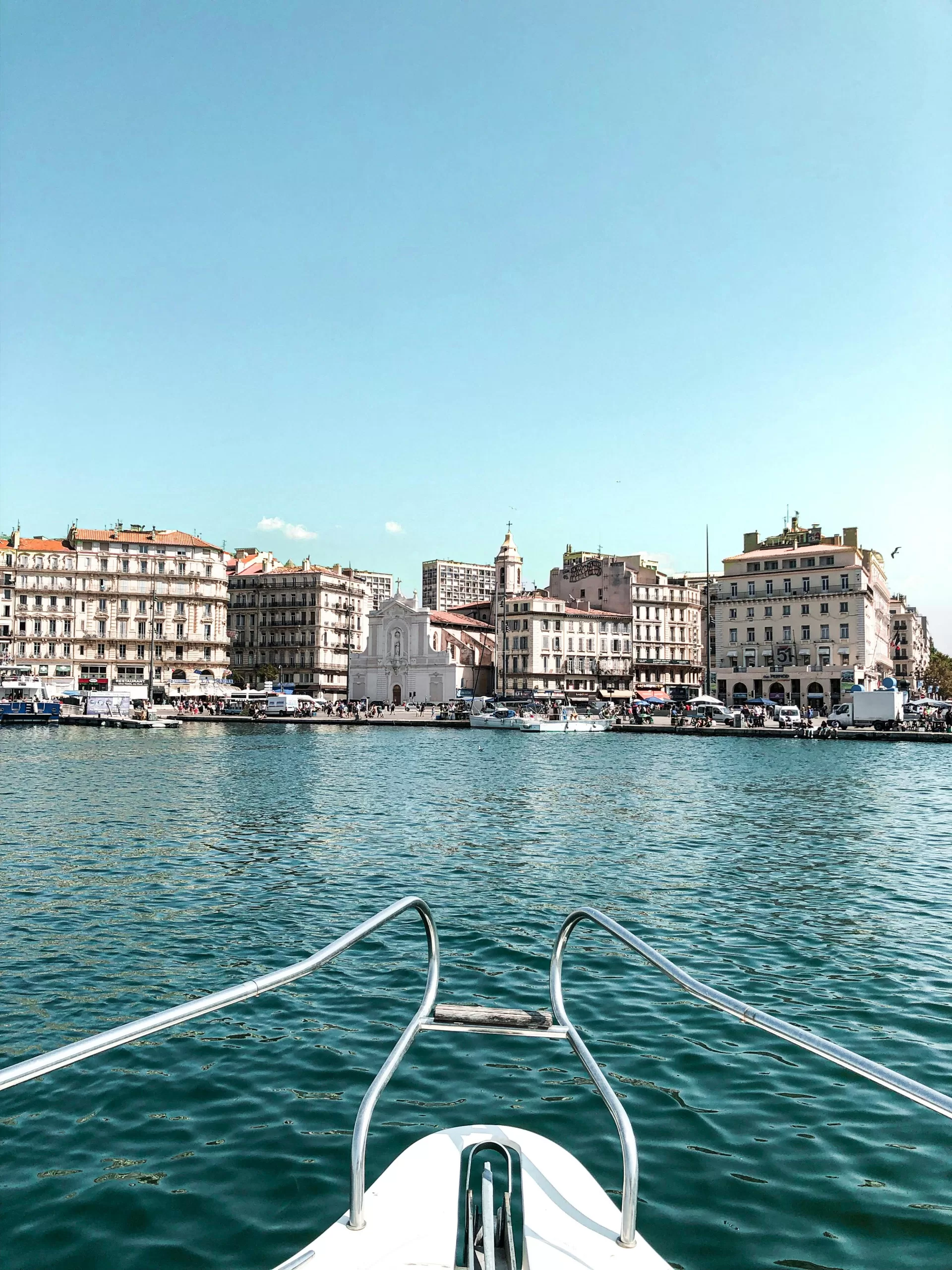 The bow of a sleek yacht approaches a sunlit European port, capturing the allure of Mediterranean summer and luxury sailing. | Elle Blonde Luxury Lifestyle Destination Blog