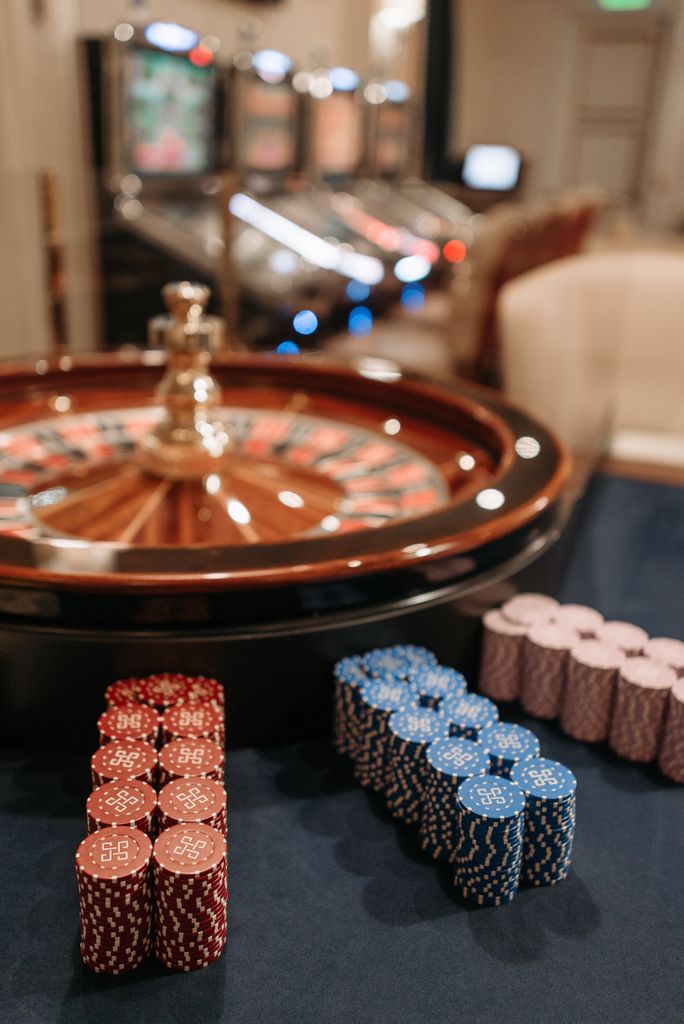 Roulette table with red, blue, and purple casino chips in focus inside a casino.