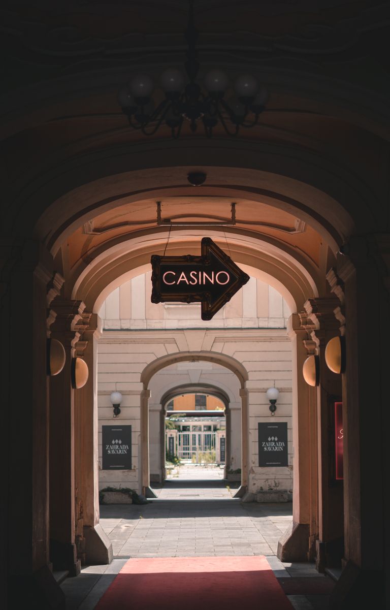 View through arched passage leading to casino, marked by a glowing arrow sign.